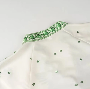 Close-up of white satin dress collar with green floral print and single-breasted detail