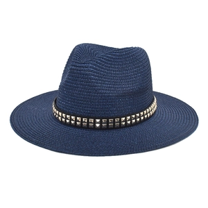 Close-up of navy blue straw fedora hat featuring a black leather band with metal studs
