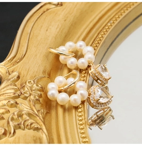 Macro shot of gold heart-shaped zircon earrings featuring circular white pearl detail
