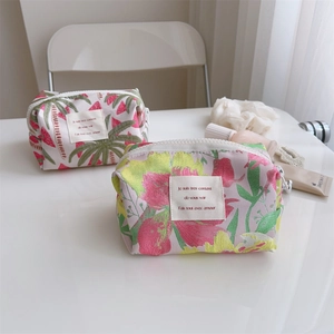 Detail of floral and tropical print fabric makeup pouches with zip closure and French label