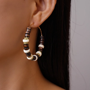Gros plan de boucles d'oreilles en perles de bois portées sur modèle pour un style boho