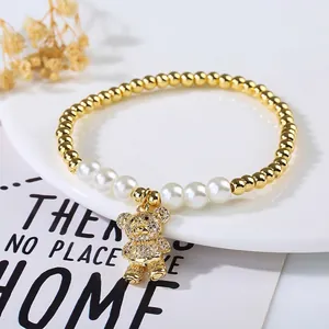 Detailed shot of a gold bear pendant with rhinestones and white pearls on a beaded bracelet