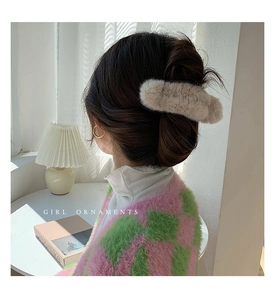 Detail of soft beige plush hair claw clip used for messy bun hairstyling in winter