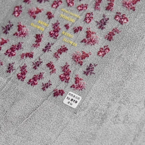 Macro detail of red vintage rose nail art stickers with ultra-thin texture on grey background