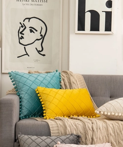 Close-up of velvet diamond quilted cushions with decorative pom-poms on a sofa