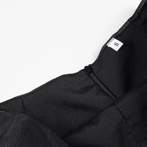 Detail of the back neckline on a black textured dress with a size S label and zipper