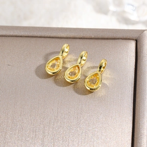 Detailed macro view of three 18k gold plated teardrop pendants with yellow zircon stones