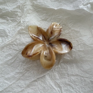 Detailansicht der Blumen-Haarklammer mit bernsteinfarbener Marmorierung auf weißem Papier