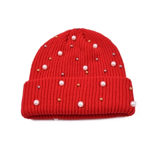 Dettaglio del berretto in maglia rossa con perle finte bianche e decorazioni metalliche