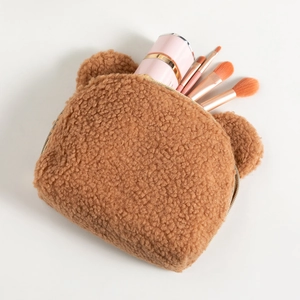 Close-up of brown teddy fleece makeup bag showing plush texture and gold metal zipper detail