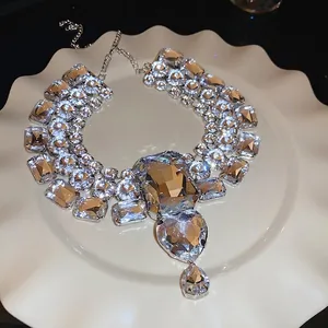 Elegant silver necklace with heart and teardrop crystals on a white porcelain plate