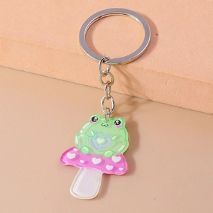 Close-up of cute green frog on pink heart mushroom keychain in glittery acrylic