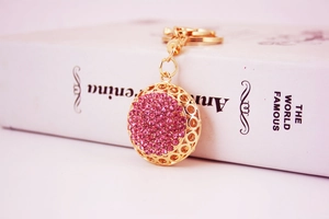 Detail of a sparkling pink rhinestone studded gold hollow sphere keychain on a book
