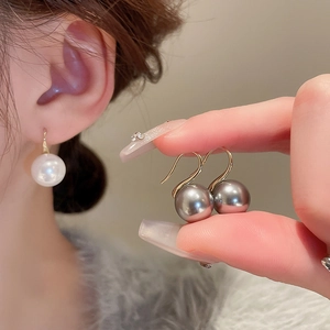 Close-up of elegant white and grey pearl earrings with minimalist gold hooks