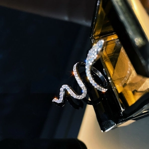 Sparkling silver snake ring with micro-set zircon stones on a dark reflective surface