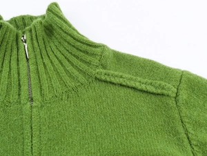 Dettaglio maglione in maglia verde con collo alto e cerniera in metallo argentato