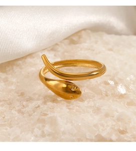 Macro detail of 18K gold plated snake ring with crystal eyes on white silk and stones