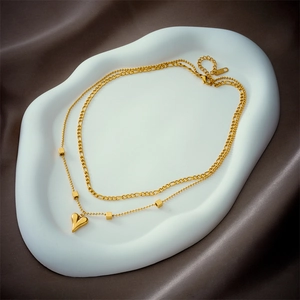 Collier double couche en titane doré avec pendentifs cœur et cubes sur présentoir
