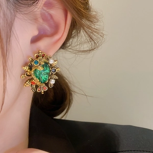 Detailed view of vintage emerald crown earrings with pearls and colorful crystals on model