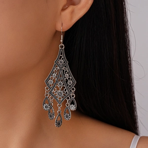 Close-up of vintage silver hollow flower drop earrings worn by a model on the ear