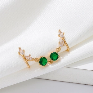 U-shaped gold nose clip with green zircons on white silk background detail shot