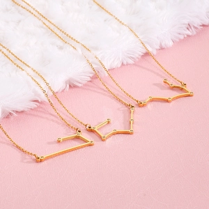 Detailed shot of three gold zodiac pendants with crystals on dainty stainless steel chains