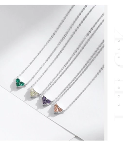 Macro shot of silver heart necklaces with vibrant green, purple and orange zircon stones