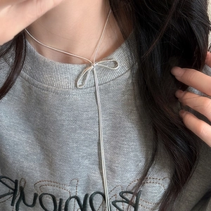 Close-up of silver bow tassel necklace on model highlighting the snake chain detail