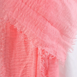Close-up of pink crinkled cotton linen scarf fabric with soft textured fringe details