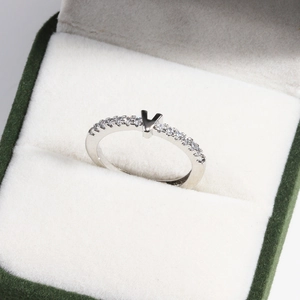 Close-up of V-shaped silver ring with inset gemstones in a green velvet jewelry box