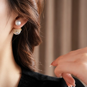 Detail von 18 Karat vergoldeten Doppelperlenohrringen mit kleinen Diamanten am Modell