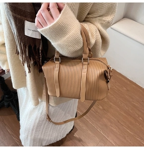 Detail of plissé pleated brown bucket bag with adjustable shoulder strap and gold hardware