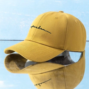 Close-up of Freedom embroidery on ginger yellow cotton canvas baseball cap with mirror reflection