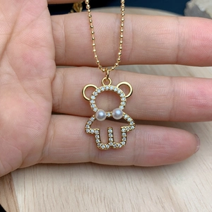 Detail of a golden bear pendant with sparkling zircons and elegant white pearls