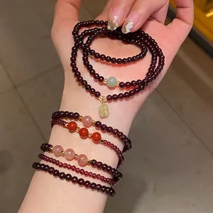 Double-layer garnet and strawberry quartz bracelet with a gold Fu pendant on model wrist