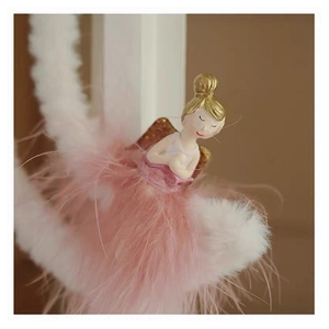 Macro detail of a pink plush angel ornament with soft feathers and golden hair accents