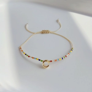 Böhmisches Armband mit bunten Miyuki-Perlen und goldenem Buchstaben-C-Anhänger auf weißem Grund