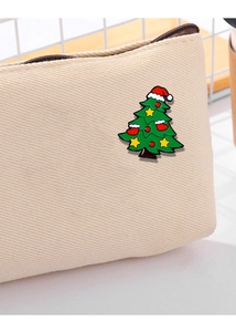 Close-up of a cute green Christmas tree metal brooch pinned on a beige canvas bag