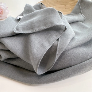 Close-up of grey knitted linen scarf texture with soft folds on a wooden tray