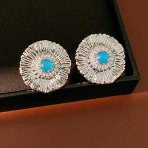 Macro shot of silver sunflower earrings with blue center stone and small white diamonds