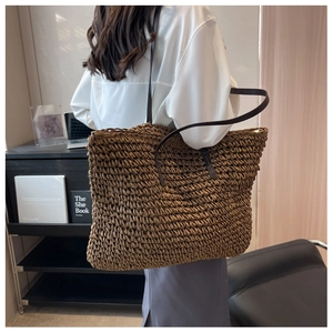 Brown woven tote bag shown from a back view on a model in a modern office setting