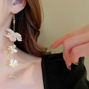 Detail of long gold chain earrings featuring gradient white flowers on a model