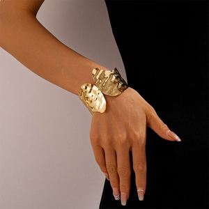Detail of wide gold cuff bracelet featuring a unique hammered texture on the metal surface