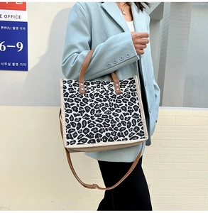 Detail of leopard print tote bag featuring brown leather handles and adjustable shoulder strap