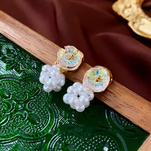 Detailed close-up of floral pearl earrings with iridescent petals on a vintage background