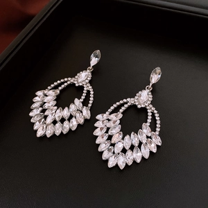 Detailed shot of sparkling rhinestone wheat ear earrings with tassels on black leather
