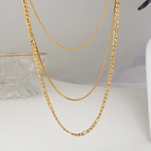 Detailed view of triple-layered golden twist, snake, and figaro necklaces set