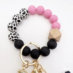 Close-up of pink and cow print silicone beads with wood accents and gold keychain