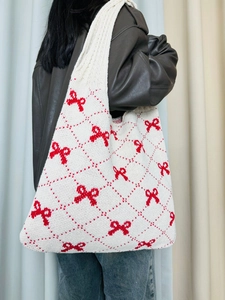 Knitted tote bag featuring red bow jacquard pattern on white textured fabric shown on model