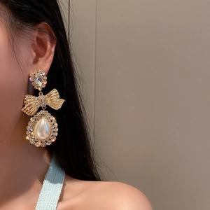 Gros plan de boucles d'oreilles nœud doré avec perles et cristaux sur un mannequin